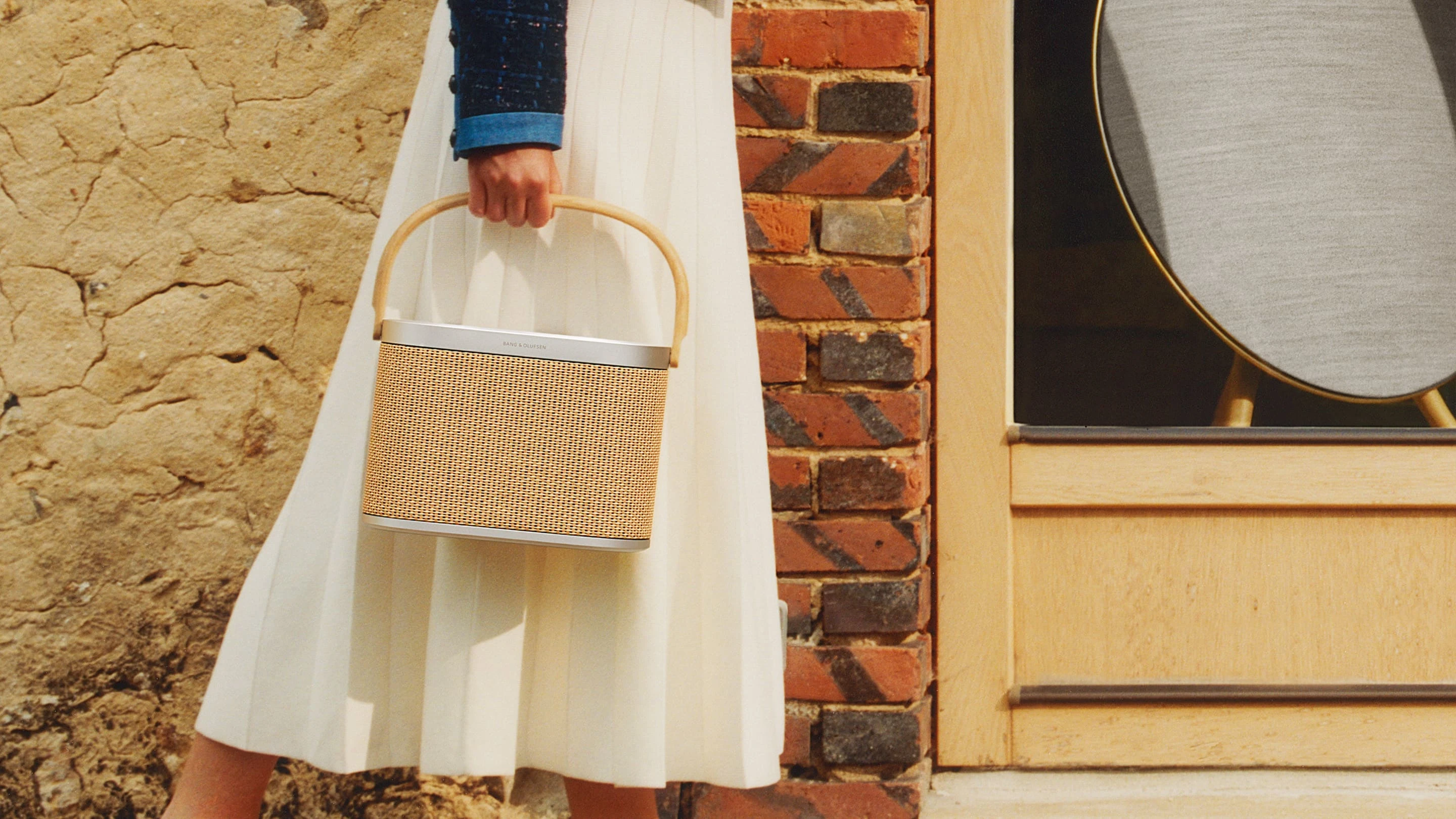 A lady is standing outside holding nordic weave Beosound A5