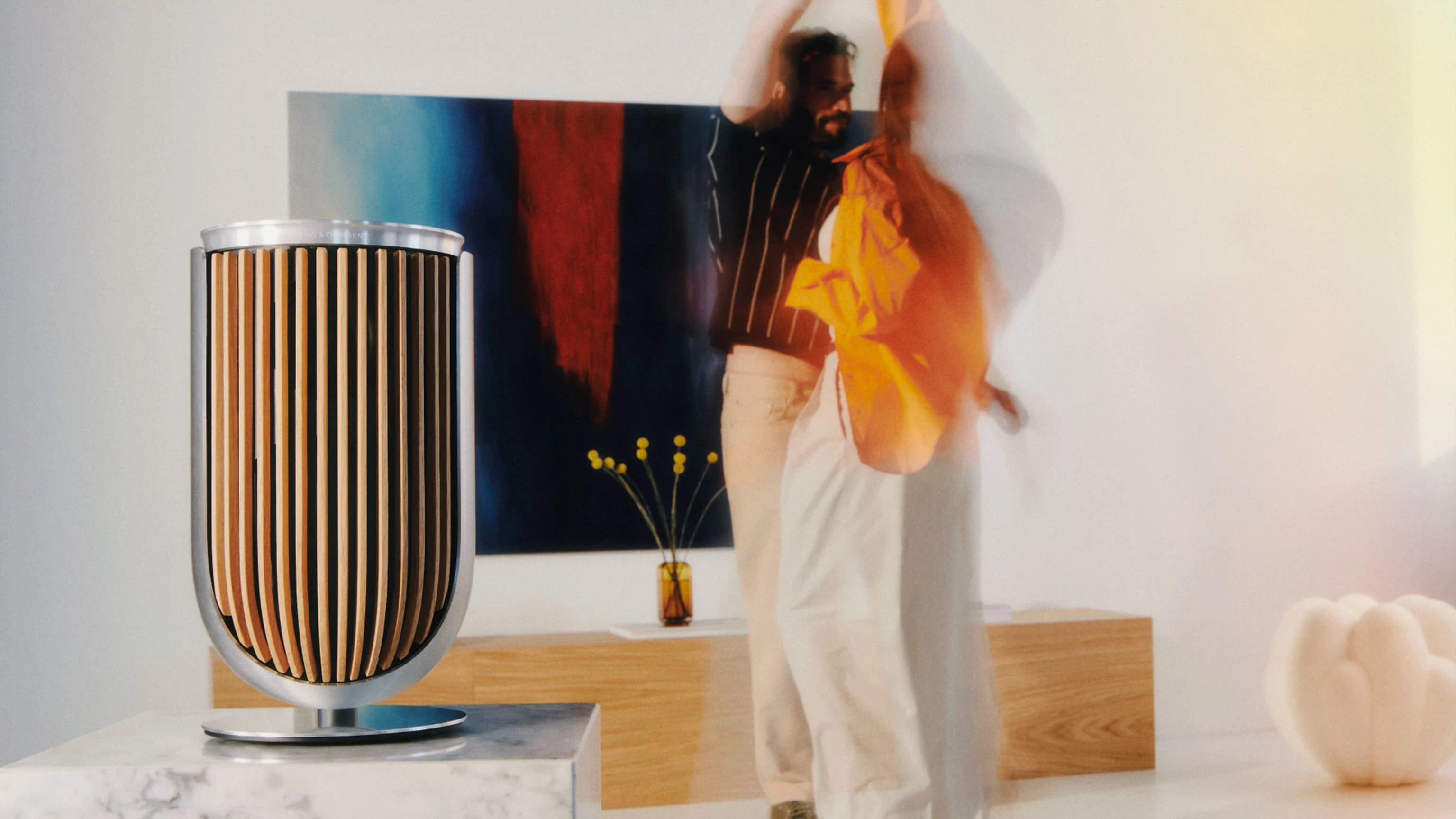 Beolab 8 in natural aluminum and light oak on a marble furniture in a living room two people dancing next to it