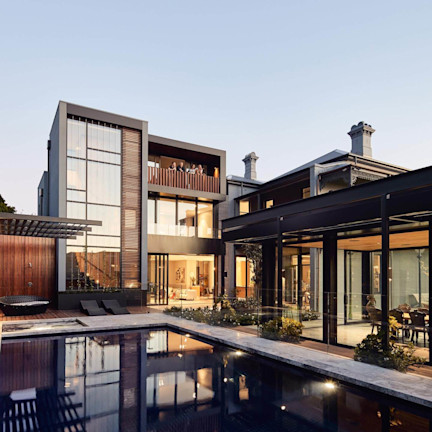 four individuals enjoying the balcony of a sleek, mostly black town house with pool.