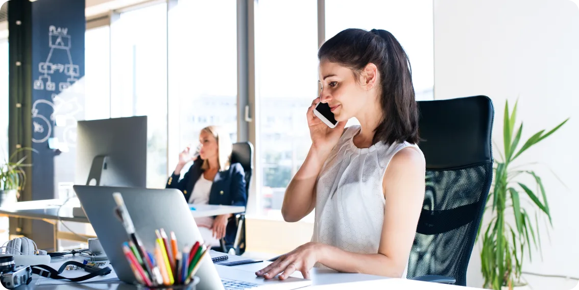 a women in the office answering phone calls while on her laptop