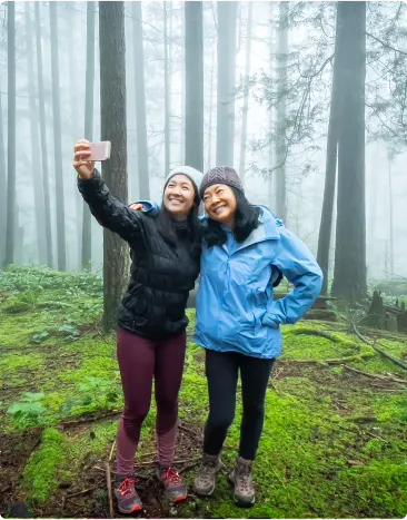 Two women taking a selfie while standing in a forest