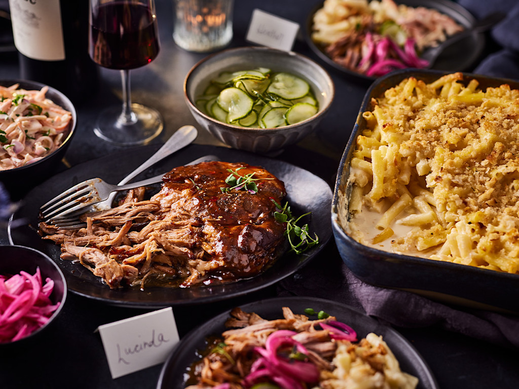 A slow cooked pork belly with macaroni cheese and glasses of red wine