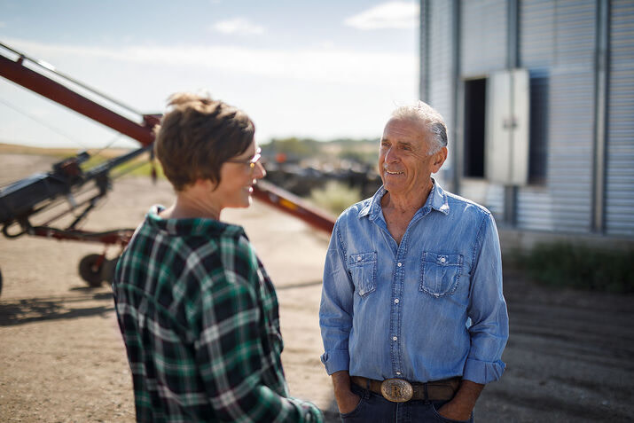 A man and woman discuss strategies in front of a grain silo, emphasizing the role of digital farming in crop production.