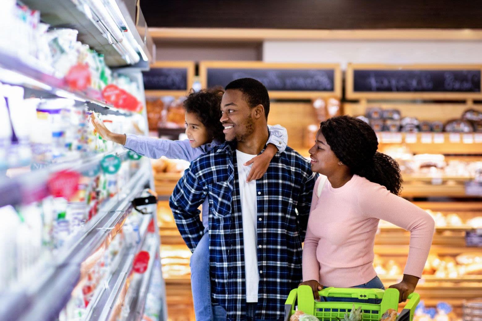 Man and daughters in grocery store dairy section.