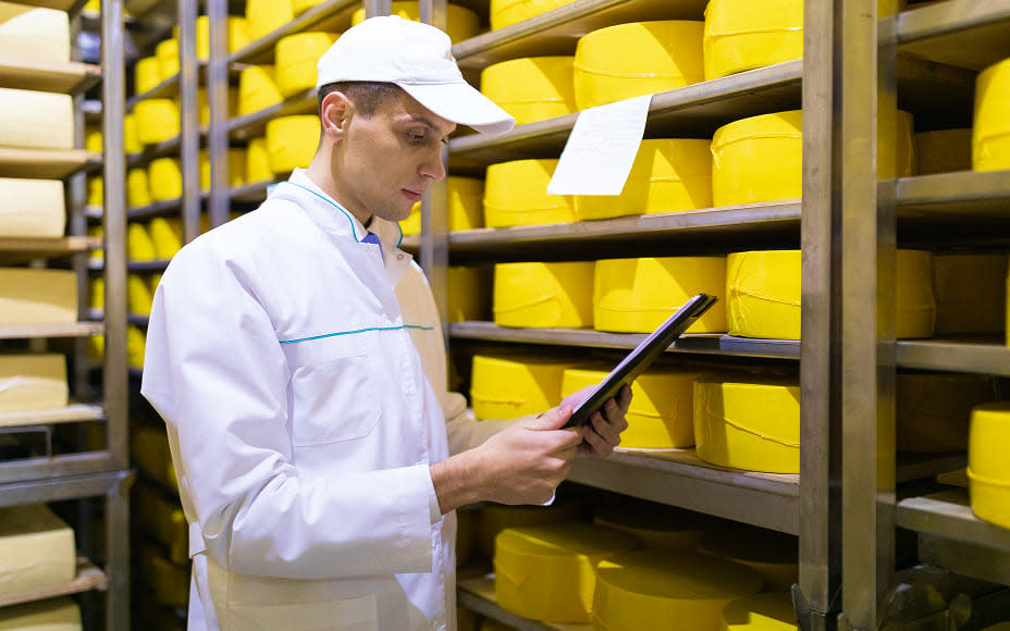 A man in a white shirt examines a tablet, likely using food safety and quality management software.