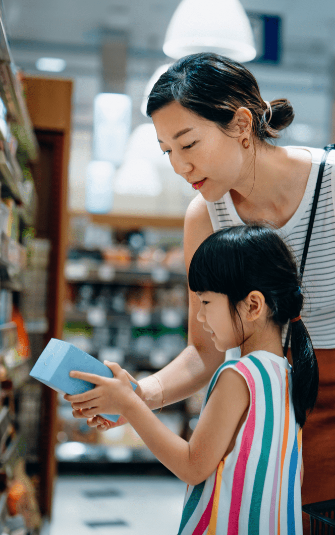 A mother and daughter shopping together in a supermarket, exploring aisles filled with various products.