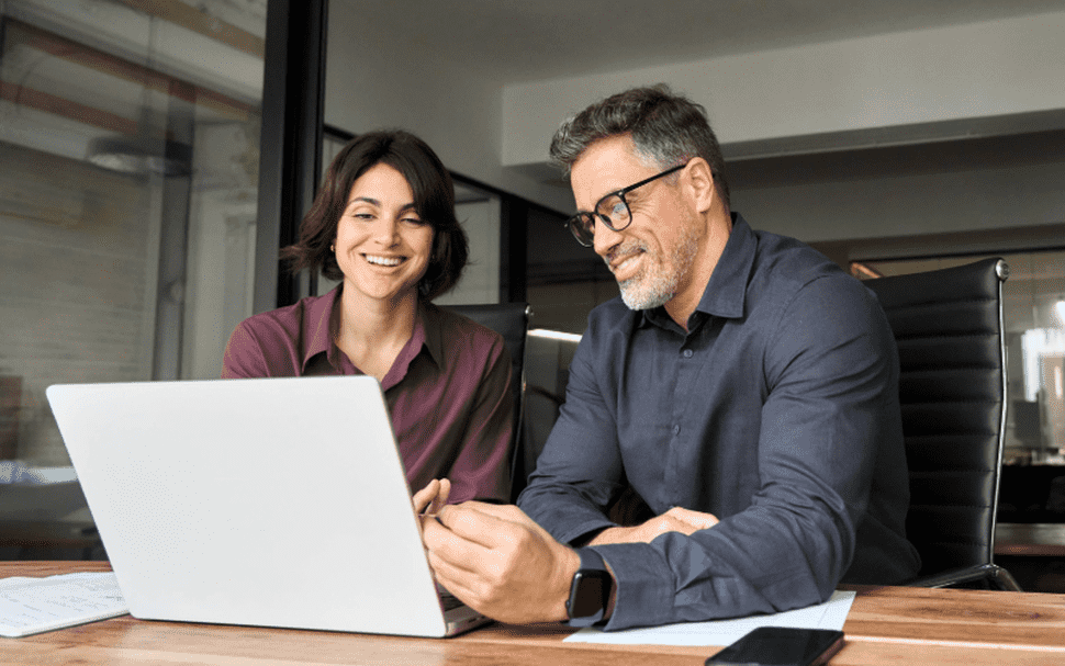 A woman and man engage in a discussion in a meeting room focused on Trade Promotion Management strategies.